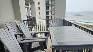 A balcony with outdoor furniture, a view of the ocean, and a building in the background. - Phoenix 6 1111 (Orange Beach)