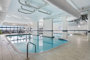 An indoor swimming pool with clear water, surrounded by tiled flooring and white pillars. - Phoenix 6 1111 (Orange Beach)