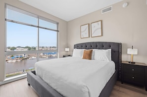 Ein modernes Hotelzimmer mit einem großen Bett, Blick auf eine Marina und die Stadtlandschaft.