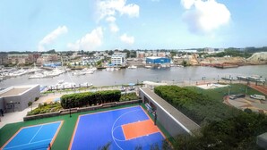 Ein Basketballplatz mit Blick auf einen Jachthafen und Gebäude im Hintergrund.
