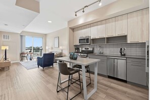 A modern kitchen with stainless steel appliances, a dining area with a table and chairs, and a view through a large window. - Stamford Waterfront Retreat (Stamford, CT)