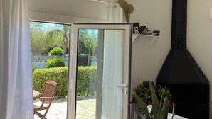 Un coin repas avec une table en bois, des chaises, un lustre, une porte-fenêtre coulissante donnant sur un patio et une cheminée noire.