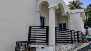 A building with a white facade, two windows, and a black gate.