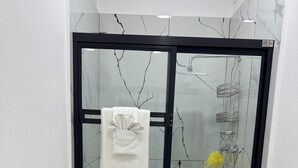 A bathroom with a glass-enclosed shower, a toilet, and a sink.