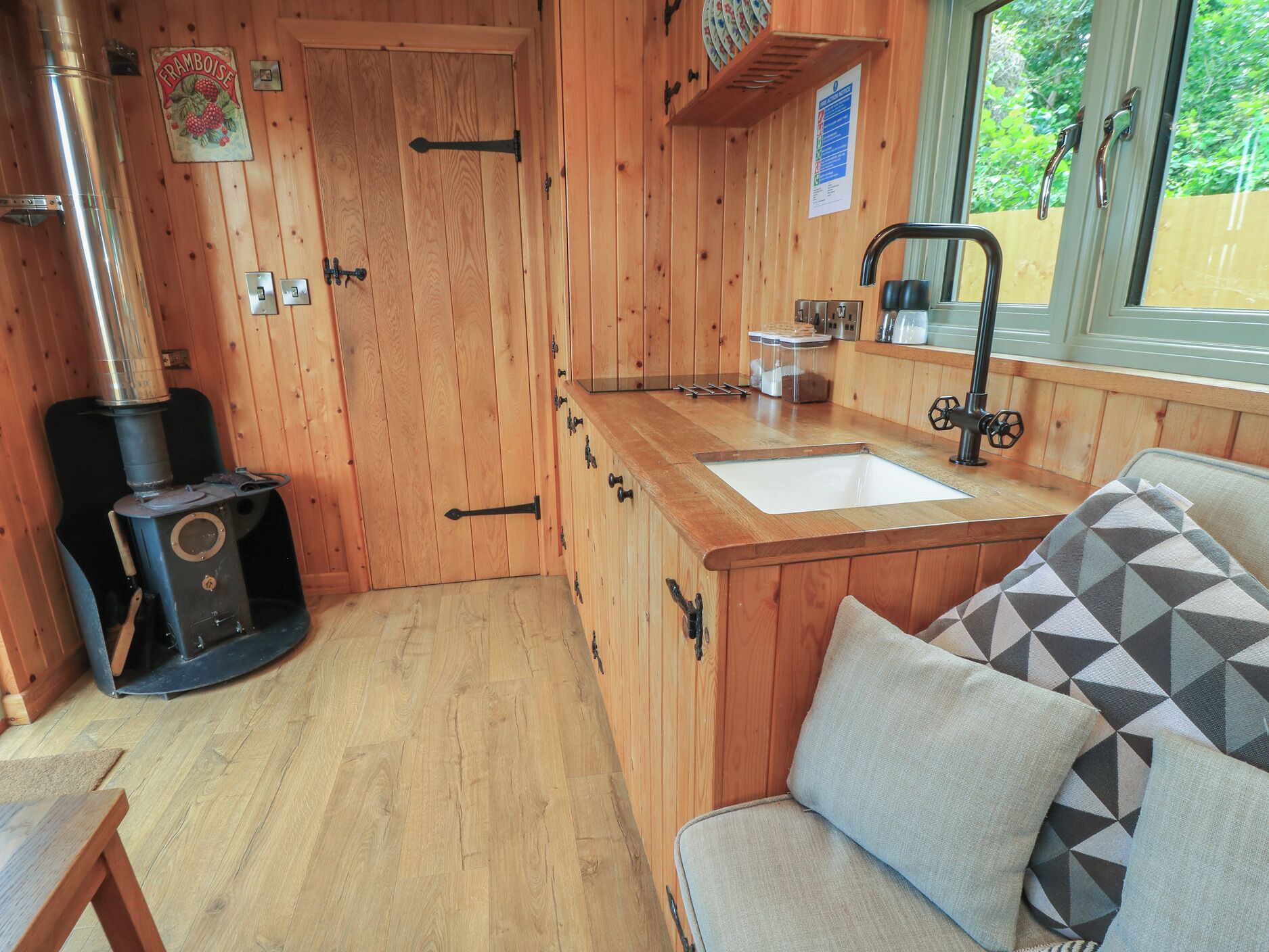Interior de madera con estufa, un lavabo y una ventana.