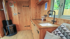 A wooden interior with a wood stove, a sink, and a window. - Pippins (Taunton)