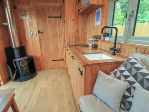 Ein Holzinnenraum mit Holzofen, Spüle und Fenster.
