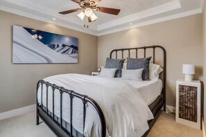 A bedroom with a bed, a ceiling fan, a nightstand, a lamp, and a painting on the wall. - Yampa Suite at High West Spa House (Glenwood Springs)