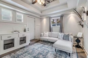A modern living room with a white sofa, a patterned rug, and a ceiling fan. - Yampa Suite at High West Spa House (Glenwood Springs)