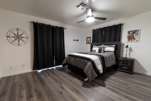Ein Schlafzimmer mit Bett, Nachttisch, Deckenventilator, Wanduhr und einer Kompass-Dekoration.