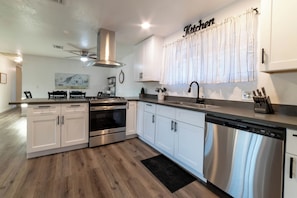 Eine moderne Küche mit weißen Schränken, Edelstahlgeräten und einem Schild mit der Aufschrift 'Kitchen'.