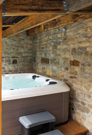 A stone-walled room with a hot tub, wooden beams, and a bench. - Villa Saulex - Luxury & comfort, swimming pool, and hot tub in the heart of Turenne. Chill & Play (TURENNE)