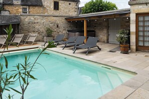 A swimming pool with lounge chairs, a hot tub, and stone walls. - Villa Saulex - Luxury & comfort, swimming pool, and hot tub in the heart of Turenne. Chill & Play (TURENNE)