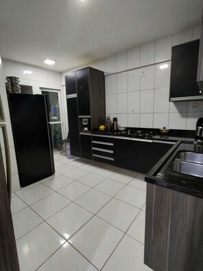 Una cocina moderna con azulejos blancos, muebles negros y un lavamanos de acero inoxidable.