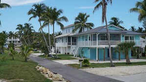 Un hôtel situé en bord de mer, avec une structure à deux étages, une véranda et une vue dégagée sur l’océan.