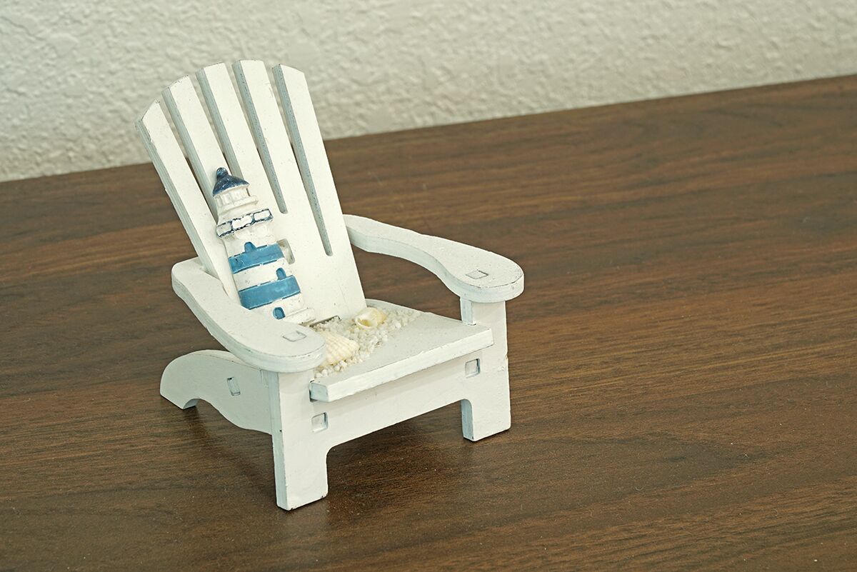 A small, white, wooden chair with a striped backrest and a small table in front.