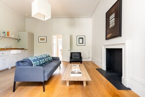 Ein Wohnzimmer mit Sofa, Couchtisch, Kamin und Küchenbereich.