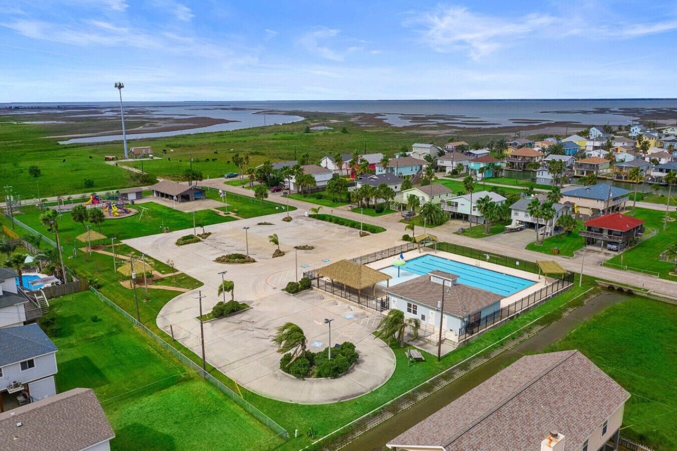 Zona residencial con piscina, casas y un amplio campo abierto.