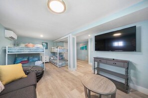 Una habitación con literas, televisor, escritorio y silla.