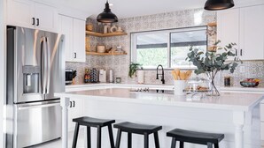 Une cuisine moderne dotée d’appareils électroménagers en acier inoxydable, de meubles blancs et d’une grande fenêtre.