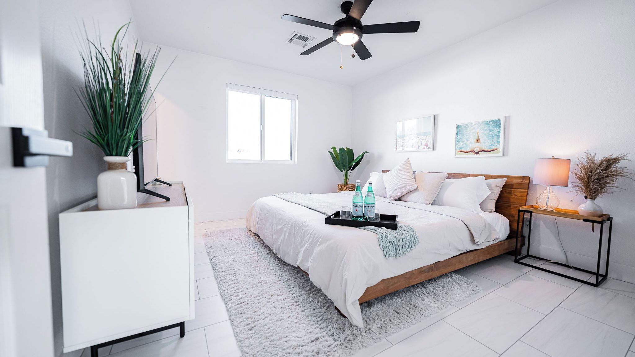 A bedroom with a bed, bedside table, lamp, and a ceiling fan.