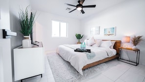 A bedroom with a bed, bedside table, lamp, and a ceiling fan.