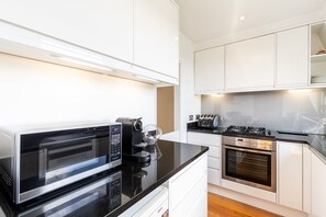 Eine moderne Küche mit einer schwarzen Mikrowelle, einer Kaffeemaschine, einem Toaster und Edelstahlgeräten.