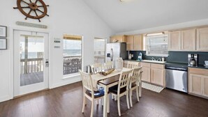 A kitchen with wooden cabinets, a stainless steel refrigerator, and a dining area with a table and chairs.