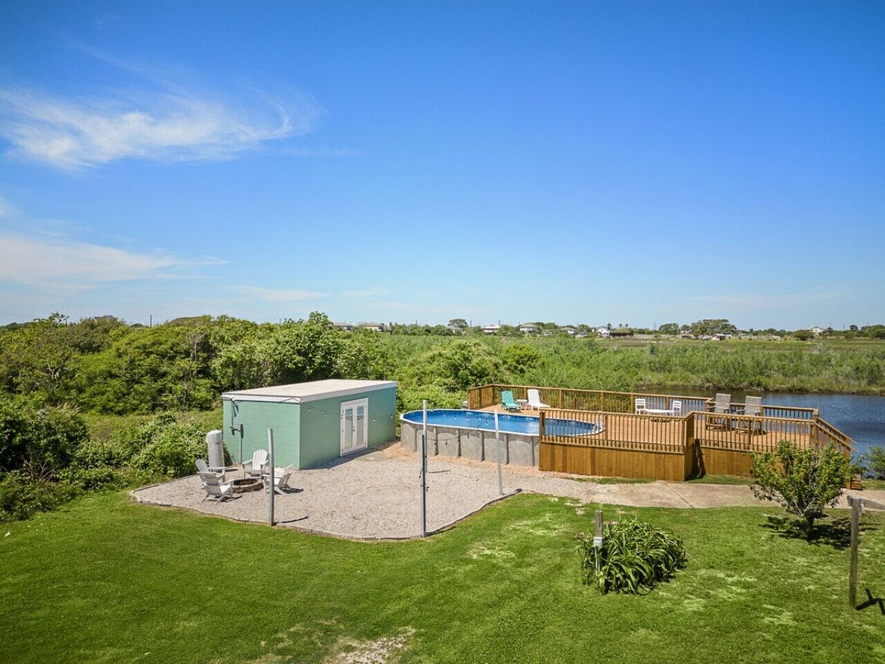 A backyard with a swimming pool, a shed, and a wooden deck overlooking a body of water.