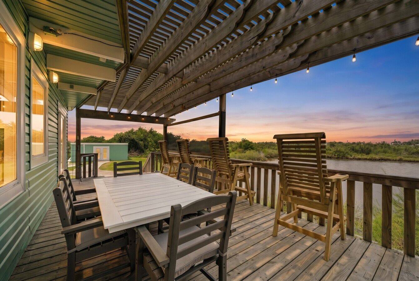 Eine Holzterrasse mit Tisch und Stühlen mit Blick auf ein Gewässer.