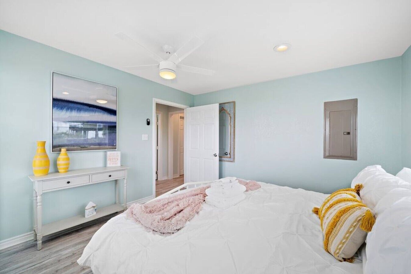 A bedroom with a bed, a ceiling fan, a dresser, and a mirror.