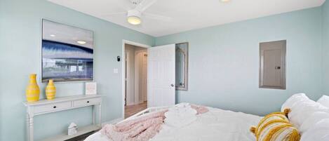 A bedroom with a bed, a ceiling fan, a dresser, and a mirror.