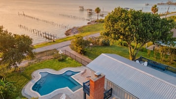 A residential property with a swimming pool, a deck, and a view of the ocean.