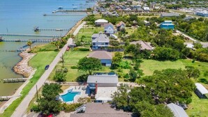 Vista aérea de una zona residencial con casas, una piscina y un muelle que se adentra en el agua.