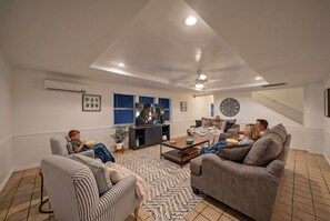 A living room with a sofa, chairs, a coffee table, and a TV.