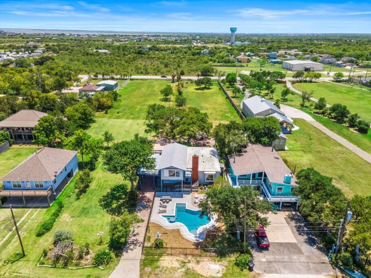 Una amplia casa con piscina, rodeada de un césped cuidado y árboles.
