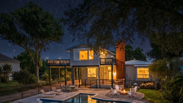 Una casa con piscina, mobiliario de exterior y un patio cubierto.