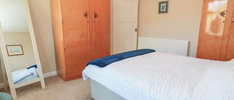 A bedroom with a bed, a wardrobe, a door, and a framed picture on the wall.