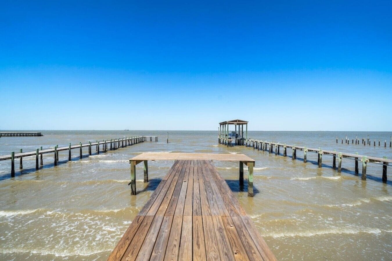 A wooden pier extending into calm waters with a gazebo at the end.