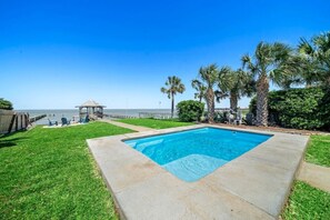Une piscine avec vue sur l’océan, entourée de palmiers et agrémentée d’un kiosque.