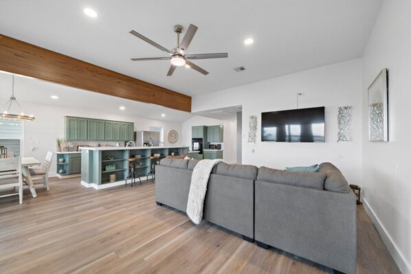 Un espacio habitable moderno con cocina, comedor y un sofá grande de color gris.