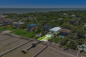 Vista aérea de una propiedad costera con piscina, varias casas y zona de playa.