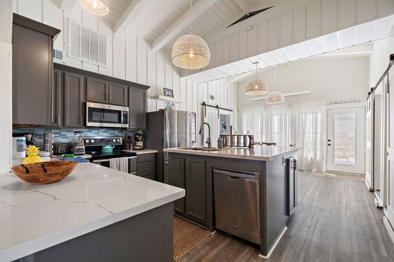 A modern kitchen with a large island, stainless steel appliances, and pendant lighting.