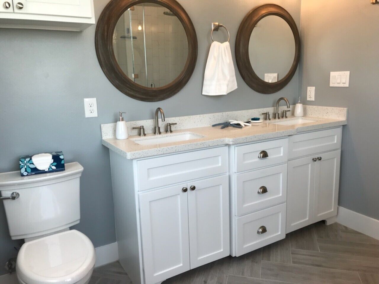 A bathroom with a white toilet, two sinks with faucets, and two round mirrors.