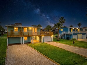 A two-story house with a balcony, a garage, and a well-maintained lawn. - Cozy Beach House w/ Fire Pit, Deck & Game Room (Jamaica Beach)