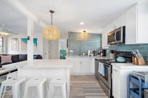 Een moderne keuken met witte kasten, een centraal eiland, een fornuis en een magnetron.