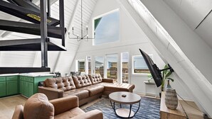 Ein geräumiges Loft mit einem großen Ledersofa, einem runden Couchtisch und einem an der Wand befestigten Fernseher.