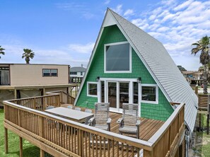 A single-story house with a green exterior and a wooden deck.
