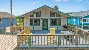 A two-story house with a porch, wooden deck, and outdoor seating. - Canal Home with Two Docks and Large Gameroom (Surfside)