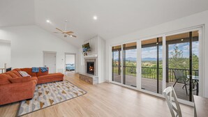Een ruime woonkamer met een open haard, een grote bank en een balkon met uitzicht.
